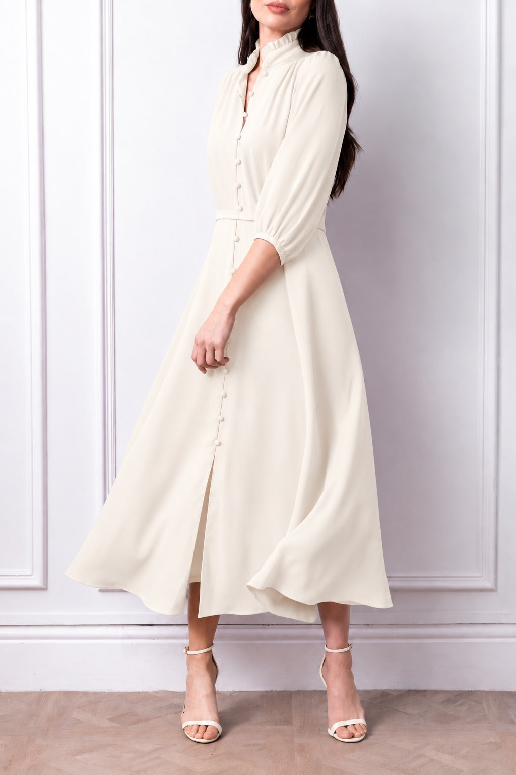 Front three-quarter view of the Aurelia ivory dress, with frill collar, covered buttons, matching belt and flared skirt.