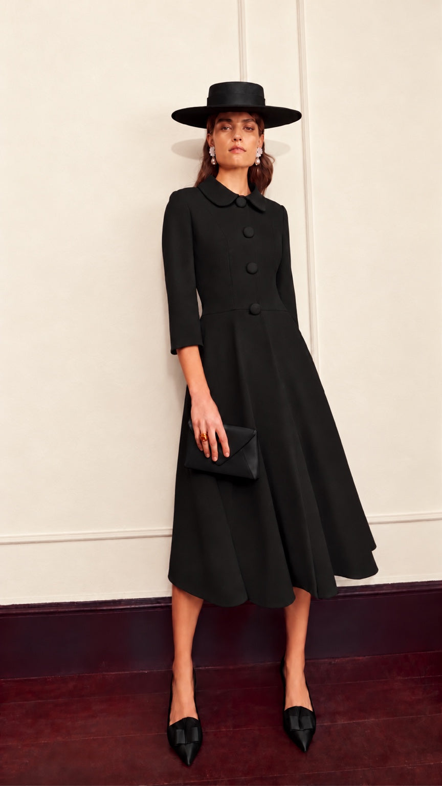 Grace black coat dress by Claire Mischevani, with rounded collar, covered buttons, three-quarter sleeves and flared skirt.