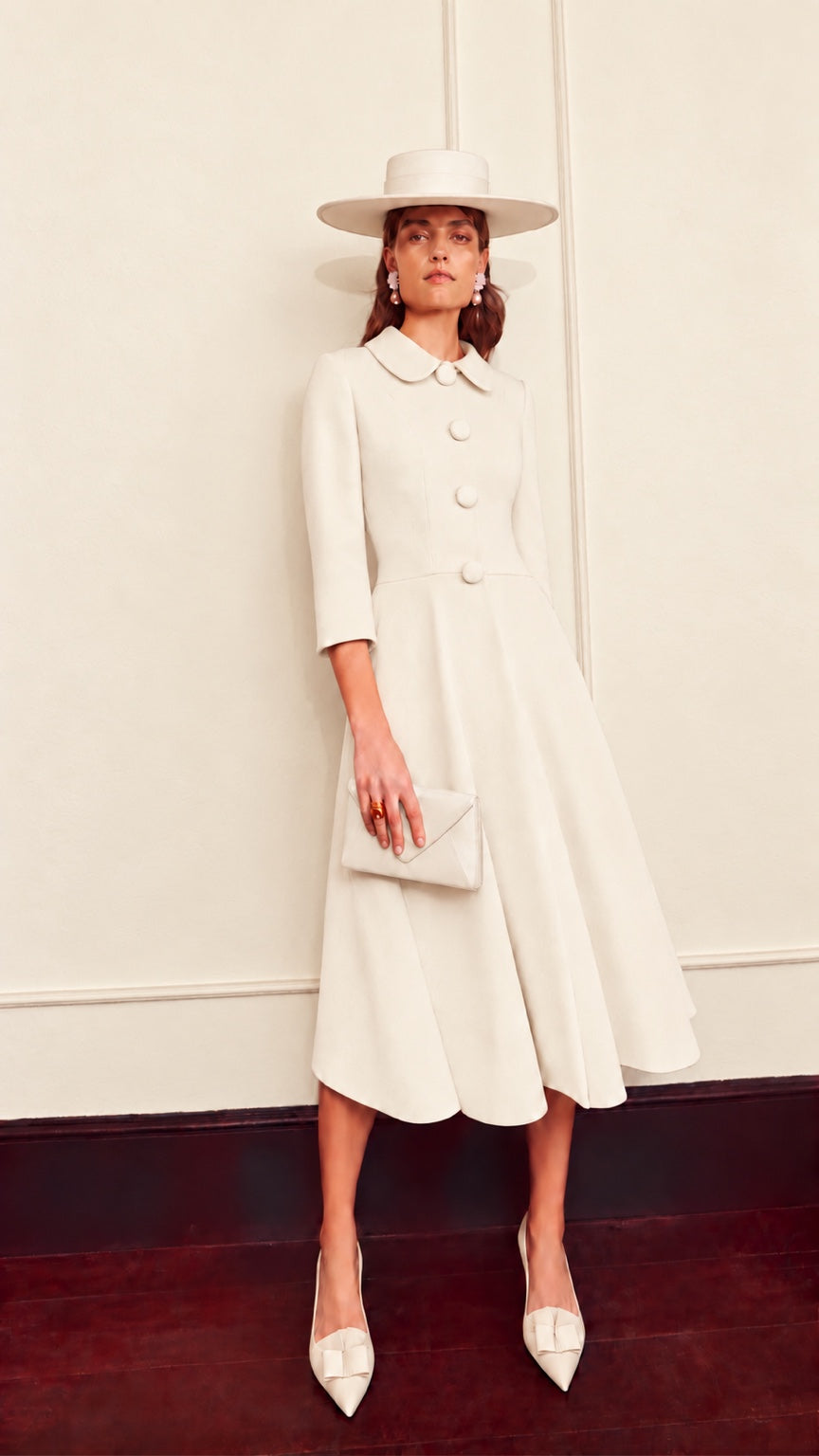 Grace ivory coat dress by Claire Mischevani, with rounded collar, covered buttons, three-quarter sleeves and flared skirt.